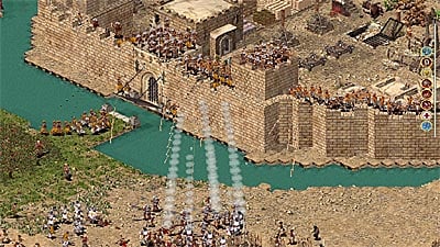 Screenshot of Stronghold: Crusader Extreme, depicting catapults firing across a moat at a fortress.