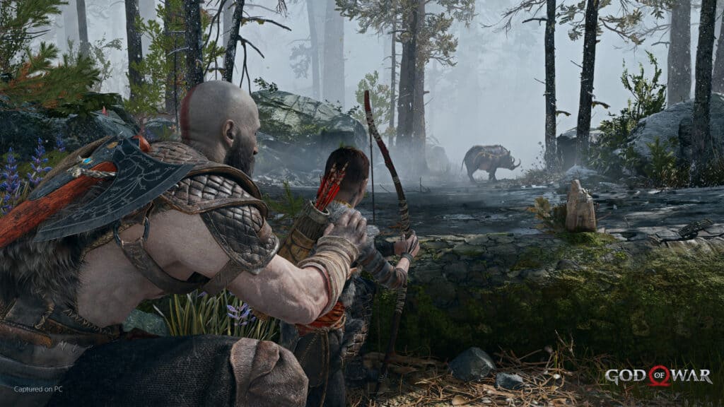 Kratos and his son kneel behind a log in God of war.