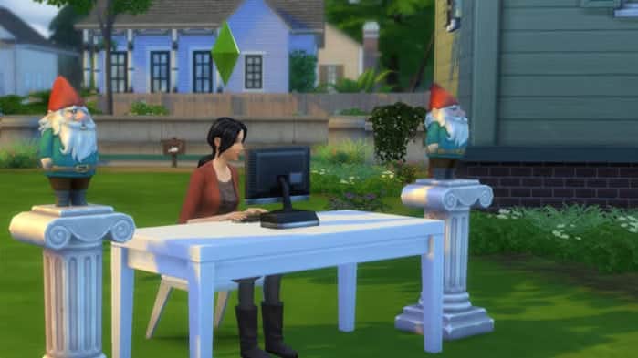 A Sim uses the computer while surrounded by gnomes.